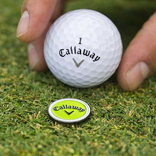 Hand placing Callaway golf ball and marker on grass